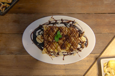 bread toast topped with chocolate, banana, almonds in a dish on the table.の写真素材