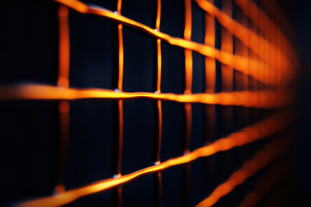 A close-up view of a metal fence illuminated by light, highlighting the texture and intricate details of the material against a contrasting background.の素材