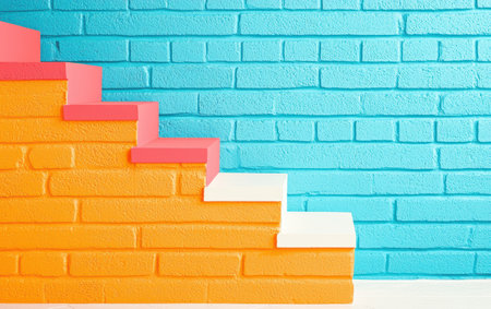 A colorful stair rests against a blue brick wall, featuring yellow and pink hues.,の素材