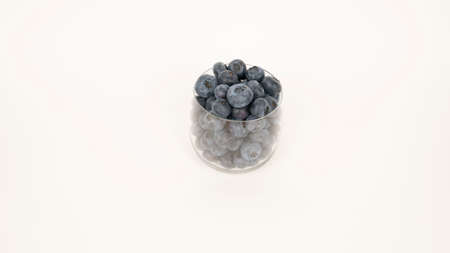 Ripe blueberries in glass closeup. Isolated on white background, blue berry