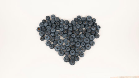 Raw blueberry heart shape on white background. Vegetarian food, blue berry cropの写真素材