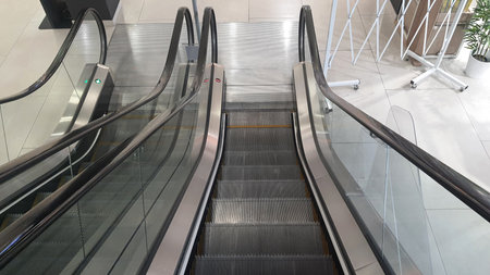 Escalators moving up and down in an empty mall evoke a sense of stillness and anticipation,...