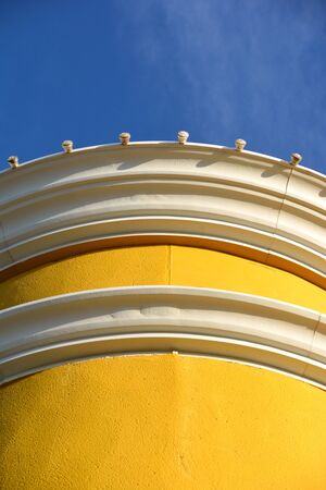A cheery yellow building against a bright blue sky on a sunny dayの写真素材