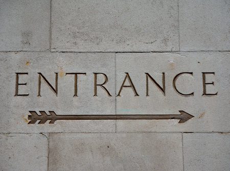 Entrance sign with arrow carved into an historic buildingの写真素材