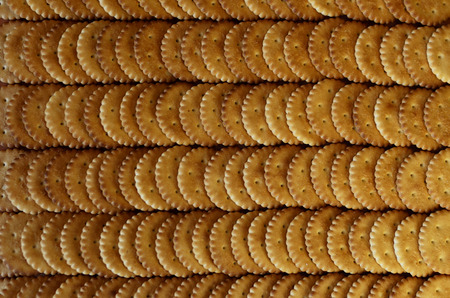 Closeup of salted crackers. Background image of classic salty cracker on a brown wooden tableの写真素材