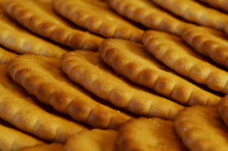 Closeup of salted crackers. Background image of classic salty cracker on a brown wooden tableの写真素材