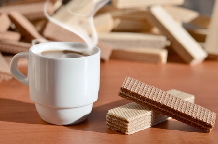 A cup of hot coffee and a handful of classic Russian waffles with different fillings on a brown wooden surface. Still-life of morning feast, concept sweets for tea or coffeeの写真素材