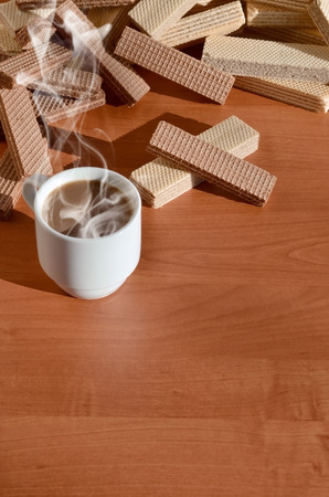 A cup of hot coffee and a handful of classic Russian waffles with different fillings on a brown wooden surface. Still-life of morning feast, concept sweets for tea or coffeeの写真素材