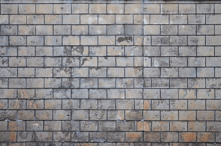 Weathered stained old block wall background. Texture of an old wall of several floors with lots of rows of blocksの写真素材