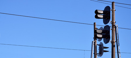 Railroad traffic light against clear blue sky, Contact wire. High voltage railroad power lines on neutral blue sky background with traffic lightsの写真素材
