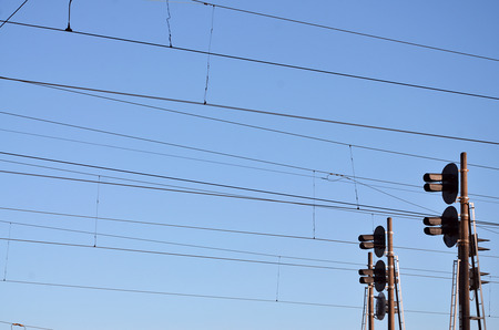 Railroad traffic light against clear blue sky, Contact wire. High voltage railroad power lines on...