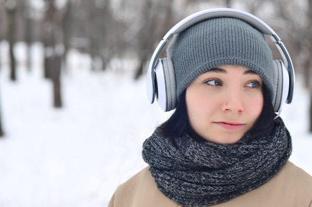 Portrait of pretty attractive caucasian pierced girl hipster winter park. She is listening to music...