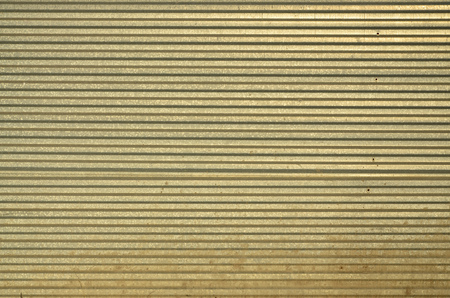 Siding, metal panels texture closeup in the daytime outdoors. Metal wall or fence embossed metal sheets. Terrain and large metal sheet as a barrier or fenceの写真素材
