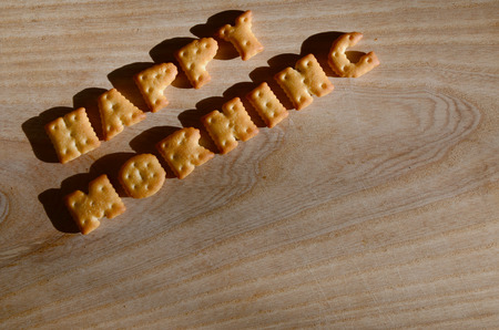 Happy morning. Text from the salty crackers as printed English letters that lie on a wooden chopping...