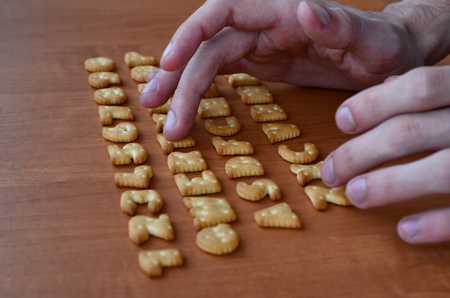 Men's fingers typing on the keyboard, which is composed of salty cracker in the form of letters and numbers. Simulating a computer keyboard using of cookies alphabetの写真素材