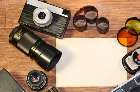 Vintage retro camera and old photography accessories on wooden surface as a background with blanks photos to placed your pictures or textの写真素材