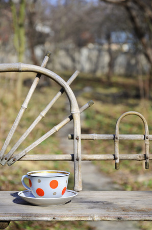 Rustic still life with a cup of tea on a wooden hand-made shelf made from old dried bamboo. Cup of hot tea in the courtyard of the spring garden. Concept of a pleasant holiday at the cottage in the villageの写真素材