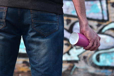Rear view of a guy drawing a wall with aerosol paint. A photography of a graffiti artist with a spray can in his hand. Concept of street art, drawing paint on the wallsの写真素材