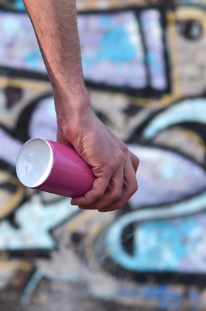 Photo of the hand of a street artist who draws a new color picture on a brick wall. One of the types of street art is the culture of youth graffiti. Decoration of walls of abandoned buildingsの写真素材