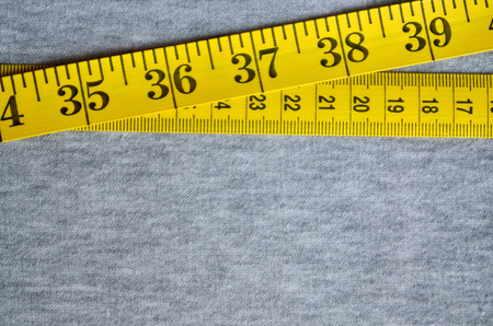 The measuring tape of yellow color with numerical indicators in the form of centimeters or inches...
