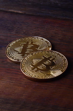 Two new golden physical bitcoins lies on dark wooden backgound, close up. High resolution photo. Cryptocurrency mining conceptの写真素材