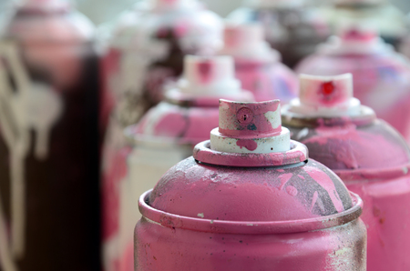 A lot of dirty and used aerosol cans of bright pink paint. Macro photograph with shallow depth of field. Selective focus on the spray nozzleの写真素材