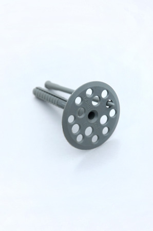 A gray plastic dowel (fastening) for thermal insulation with round umbrella caps lies on a gray foam polystyrene plateの写真素材