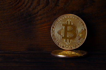 Two new golden physical bitcoins lies on dark wooden backgound, close up. High resolution photo. Cryptocurrency mining conceptの写真素材