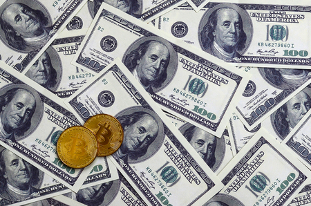 Golden bitcoins lie on a lot of dollar bills. The concept of raising the price of bitcoin relative to the US dollarの写真素材