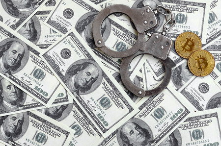 Police handcuffs and bitcoins lie on a large number of dollar bills. The concept of problems with the law during the illegal cryptocurrency mining and bitcoin operationsの写真素材