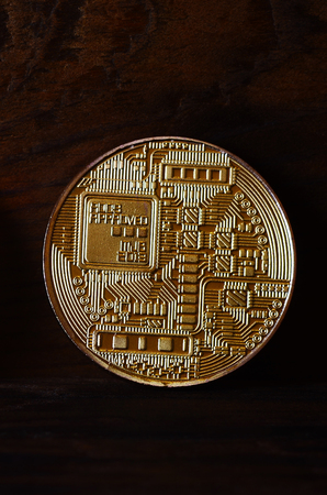 One new golden physical bitcoin is lies on dark wooden backgound, close up. High resolution photo. Cryptocurrency mining conceptの写真素材