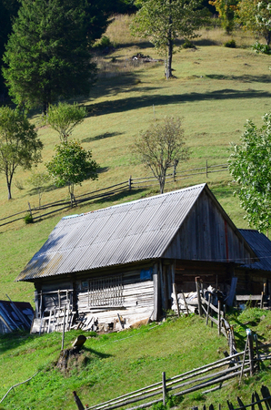 The old Ukrainian hut with a slate roof and a wooden fence in a green fieldの写真素材