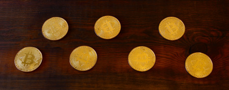 Golden physical bitcoins lies on dark wooden backgound, close up. High resolution photo. Cryptocurrency mining conceptの写真素材