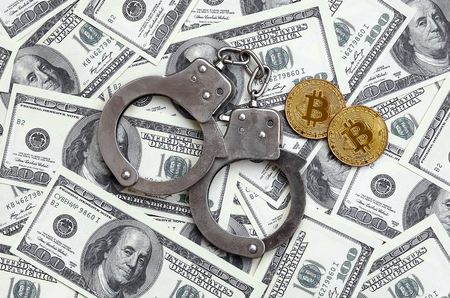 Police handcuffs and bitcoins lie on a large number of dollar bills. The concept of problems with the law during the illegal cryptocurrency mining and bitcoin operationsの写真素材