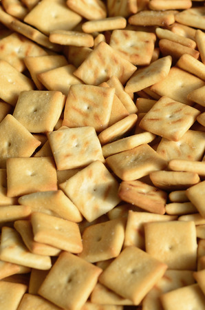 Background texture of small edible squares baked from dough and sprinkled with salt. A lot of salt crackerの写真素材