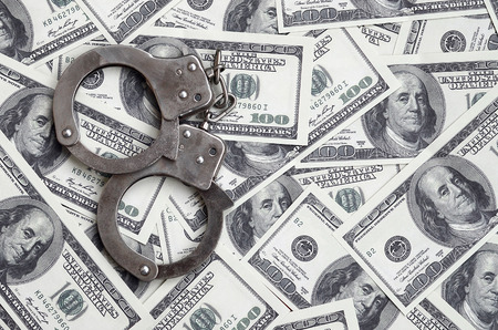 Police handcuffs lie on a lot of dollar bills. The concept of illegal possession of money, illegal transactions with US dollars. Economic Crimeの写真素材