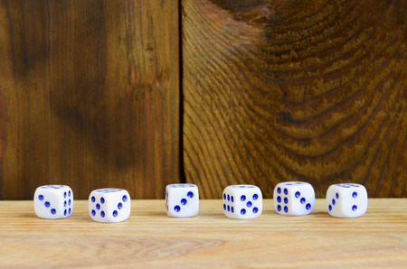 A few dice lies on the surface of natural wood. Items for generating numbers from one to six in the...