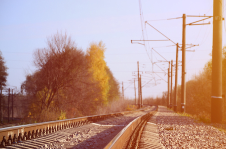 Autumn industrial landscape. Railway receding into the distance among green and yellow autumn treesの写真素材
