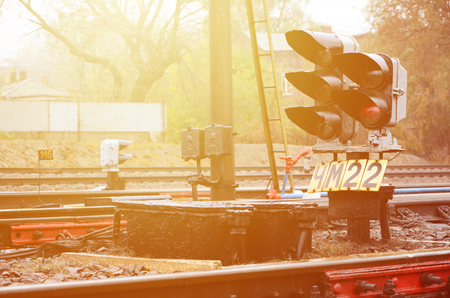 Photo of a fragment of a railway track with a small traffic light in rainy weatherのeditorial素材