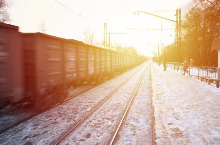 Photo of bright and beautiful sunset on a cloudy sky in cold winter season. Railway track with platforms for waiting trains and power transmission lines in the middle of winter forest landscapeのeditorial素材