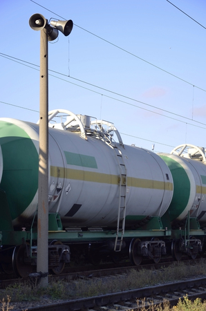 Railway landscape. Many railroad cars and tanks standing in rails. Public address horn loud speakers on wooden pole over 
blue skyのeditorial素材