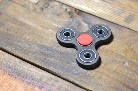 A rare handmade wooden fidget spinner lies on a brown wooden background surface. Trendy stress relieving toyの写真素材