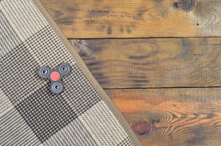A rare wooden handmade spinner lies on a checkered plaid on a brown wooden background surface. Trendy stress relieving toyの写真素材