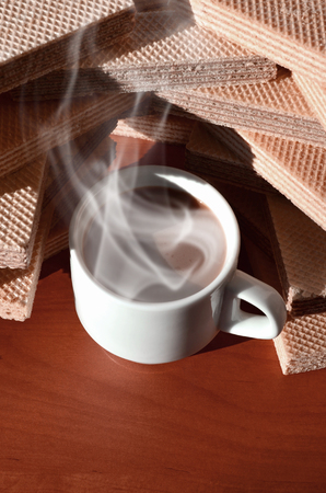 A cup of hot coffee and a handful of classic Russian waffles with different fillings on a brown wooden surface. Still-life of morning feast, concept sweets for tea or coffeeの写真素材
