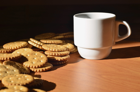 Background image of a small white cup of coffee and classic salty cracker on a brown wooden table with copyspaceの写真素材