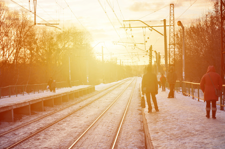 Evening winter landscape with the railway station. Snow-covered railway platform under the sun light at sunset. A place where people waiting for a trainのeditorial素材
