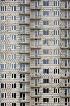 Textured pattern of a russian whitestone residential house building wall with many windows and balcony under constructionのeditorial素材