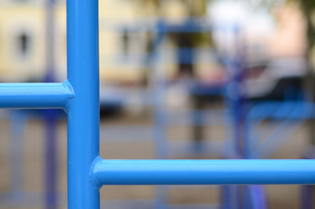 Blue metal pipes and cross-bars against a street sports field for training in athletics. Outdoor athletic gym equipment. Macro photo with selective focus and extremely blurred backgroundの写真素材