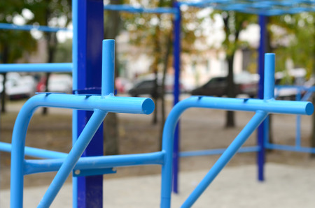 Sports bars in blue on the background of a street sports ground for training in athletics. Outdoor athletic gym equipment. Macro photo with selective focus and extremely blurred backgroundの写真素材