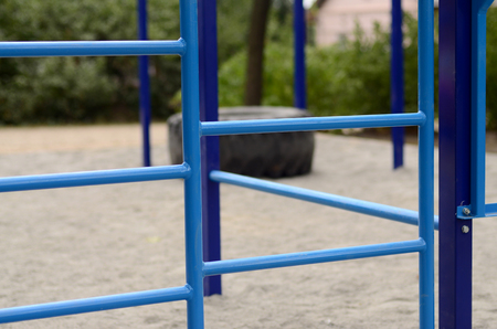 Blue metal pipes and cross-bars against a street sports field for training in athletics. Outdoor...